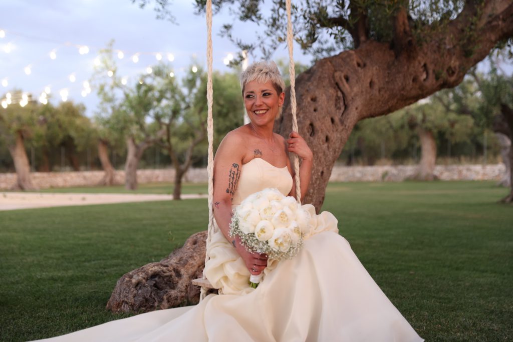 La sposa sorride accanto a un ulivo