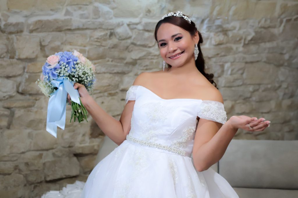 La sposa con il bouquet davanti a una parete di pietra
