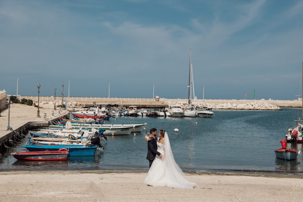 Gli sposi sulla spiaggia davanti al porto – matrimonio di Cosimo e Dominga