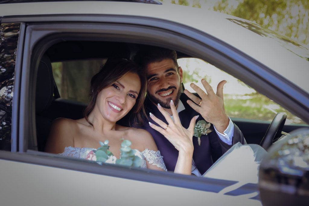 Gli sposi mostrano le fedi in automobile – matrimonio di Cosimo e Dominga
